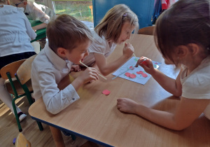 Dzieci przenoszą papierki za pomocą slomek